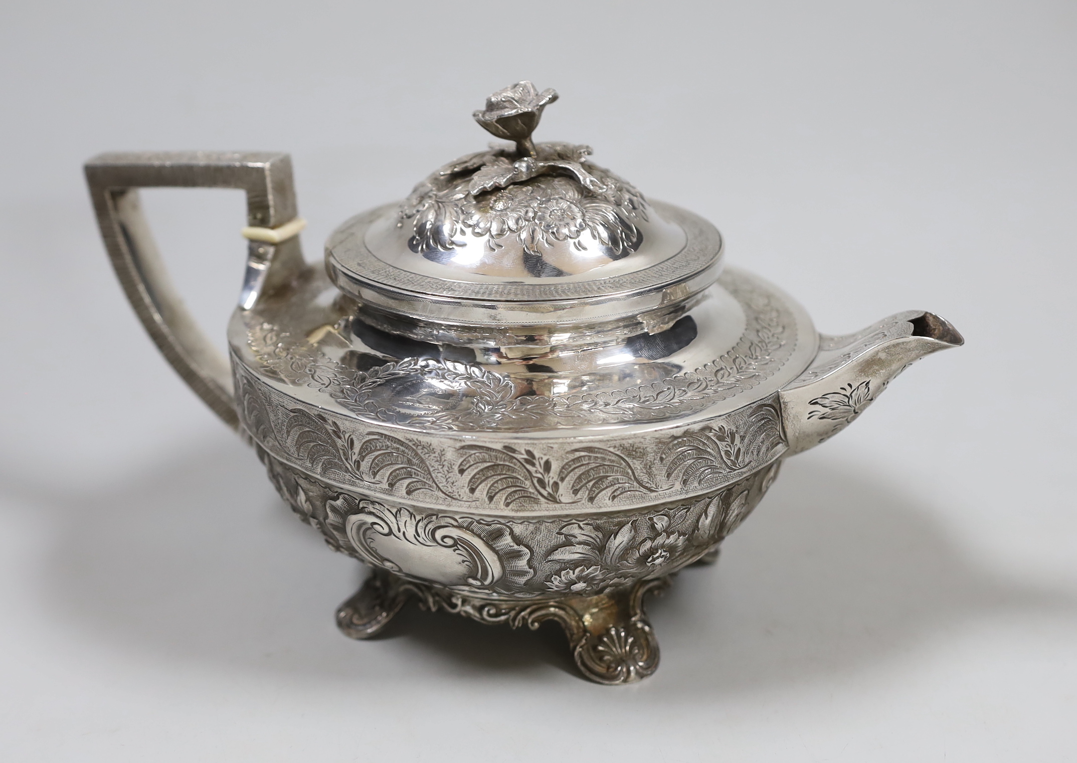 A George III engraved silver squat circular teapot, with foliate decoration and rose finial, by John Emes, London, 1803, gross weight 24.8oz. (See lot 868 for a near matching cream and sugar bowl). Ivory submission refer